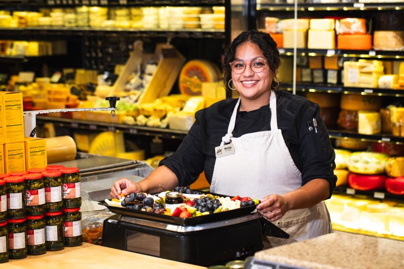 Smiling associate holding a cheese tray