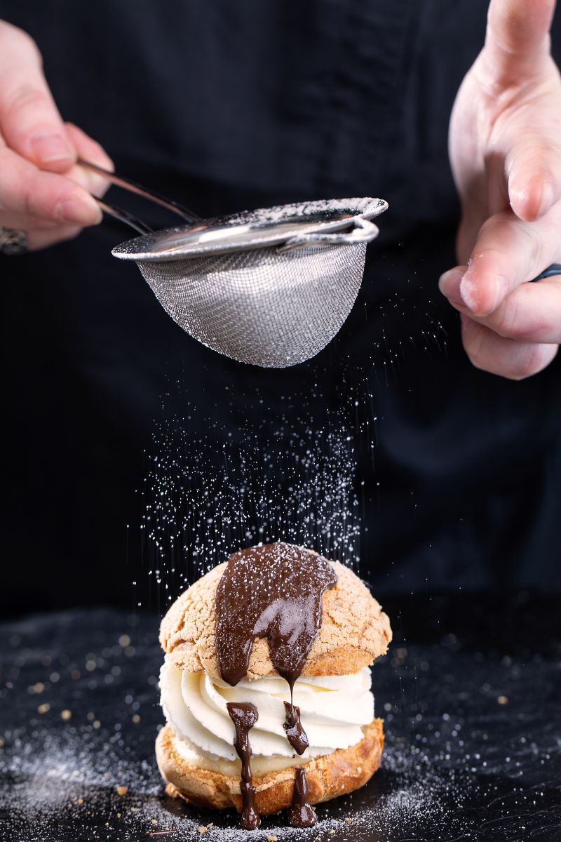 Artfully dusting powdered sugar onto a pastry