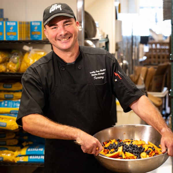 Smiling DLM associate holding a bowl of prepared food